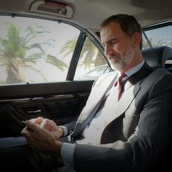 El Rey Felipe mira su movil camino a un acto oficial
