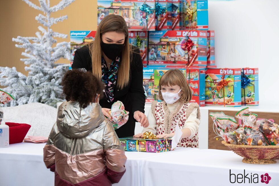 Gabriella de Mónaco da regalos a una niña en presencia de Camille Gottlieb en la entrega de regalos navideños 2021