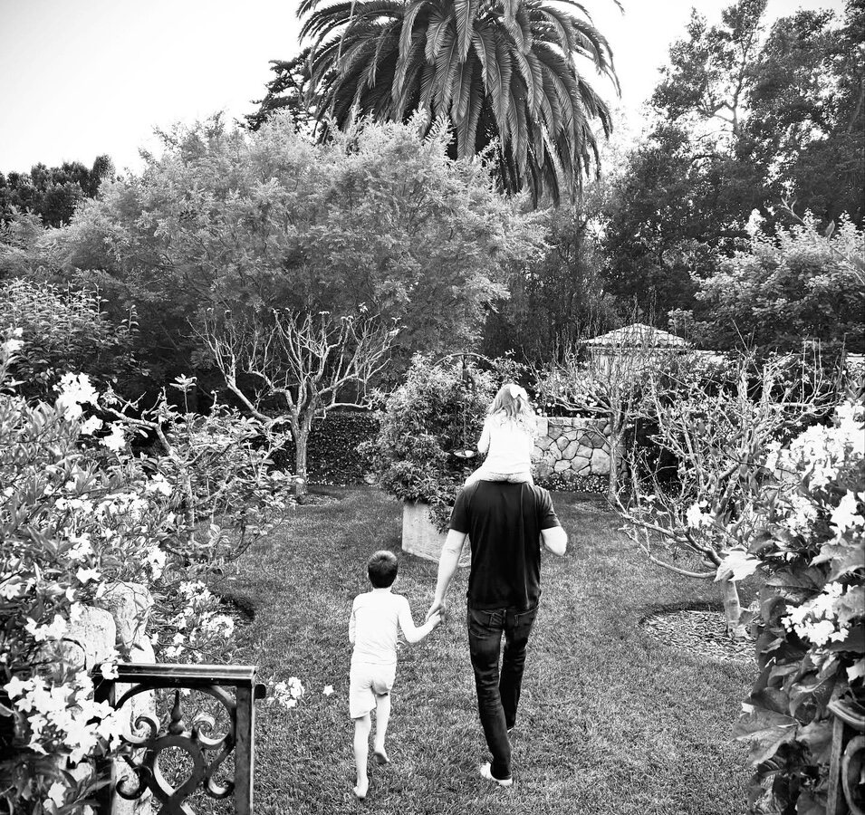 Príncipe Harry con sus hijos Archie y Lilibet caminando juntos en su jardín