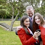 Los Reyes Felipe y Letizia y la Infanta Sofía mirando el móvil en la graduación de la Infanta Sofía