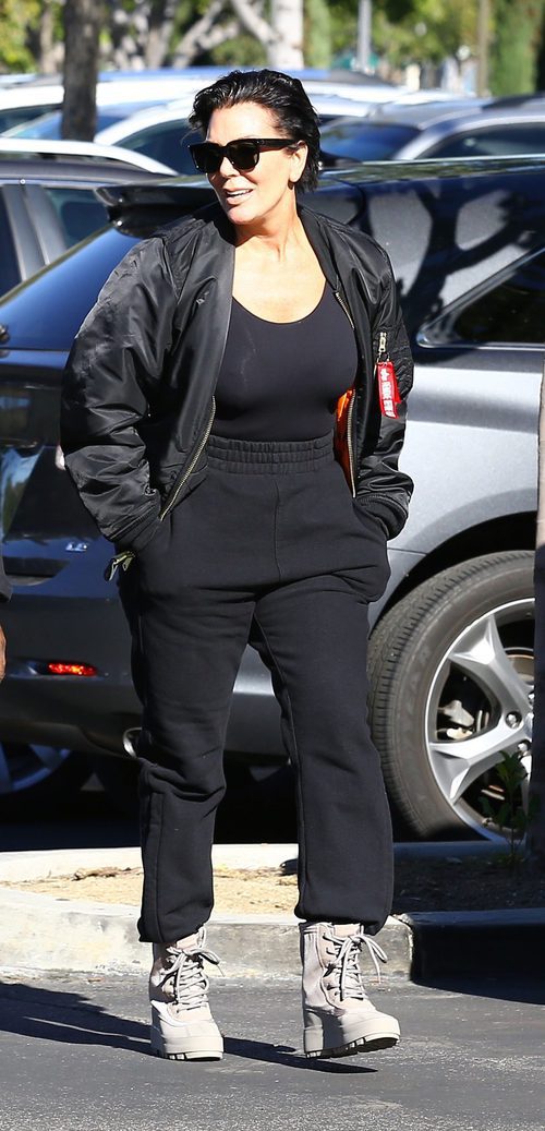 Kris Jenner paseando con chandal negro y botas de tacón beige