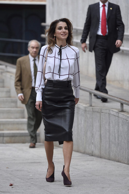Rania de Jordania con falda de tubo midi en cuero negro y blusón con lazada al cuello en su visita al centro cultural Medio-lab prado